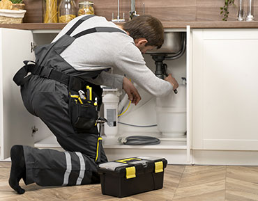 Plombier en intervention sous un evier